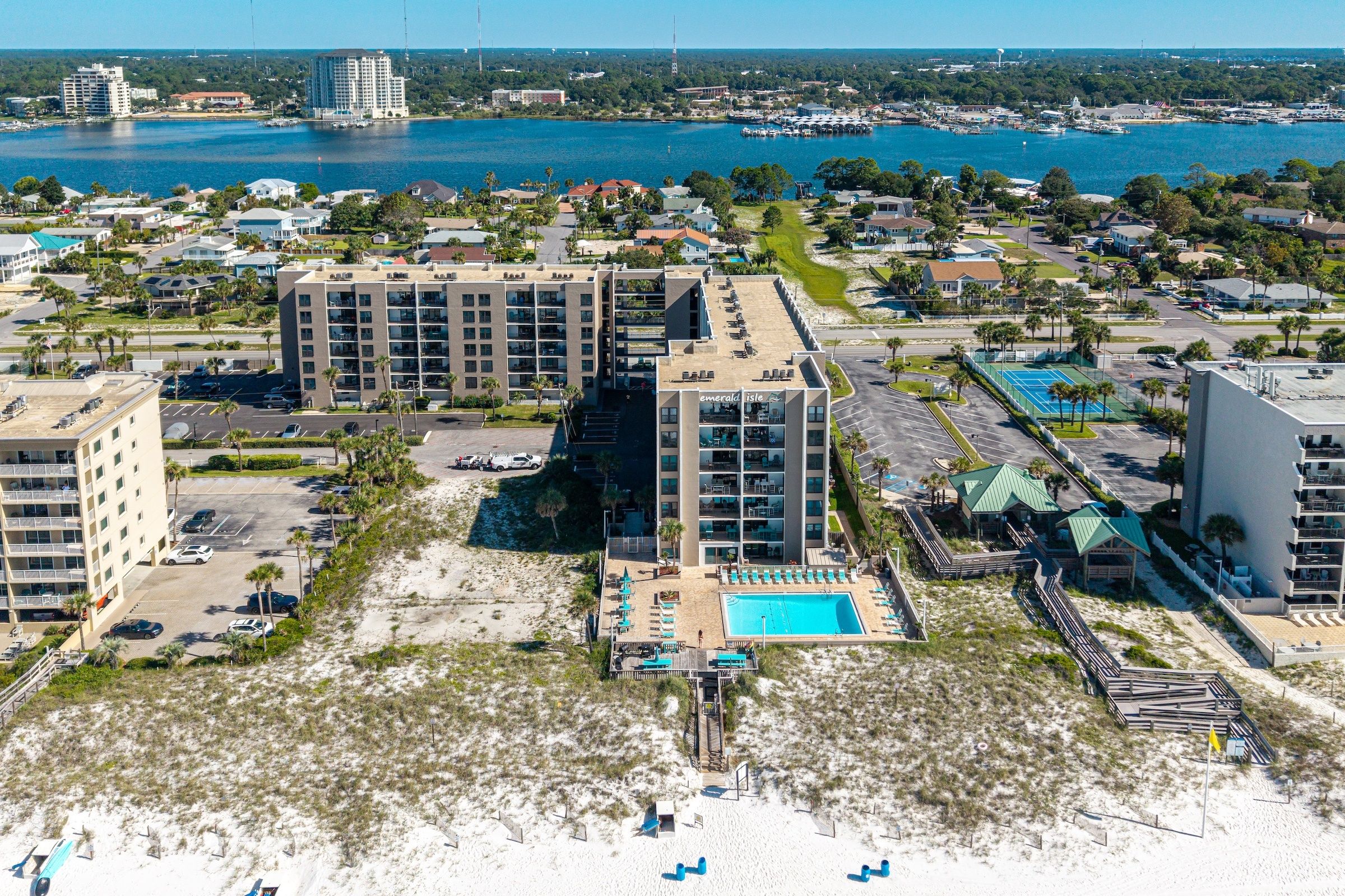 A coastal hotel with multiple buildings, a swimming pool, and a beach area.