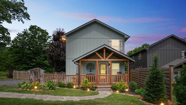 A two-story house with a front porch, a wooden deck, and a landscaped garden. - Mountain Views Basecamp West Jefferson 2 Bedroom Home (West Jefferson)