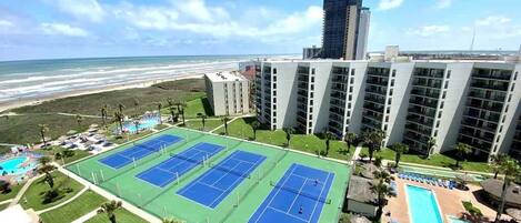 Un hotel con cancha de tenis, piscina y vista al océano.
