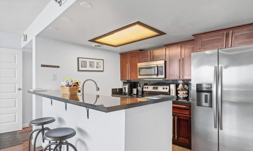 A kitchen with a central island, stainless steel appliances, wooden cabinets, and a recessed ceiling light.