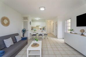 Uma sala de estar moderna com sofá, mesa de centro e área de jantar com cadeiras e mesa.