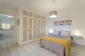 Quarto com cama, luminárias de cabeceira, obra de arte na parede e guarda-roupa com design vazado.