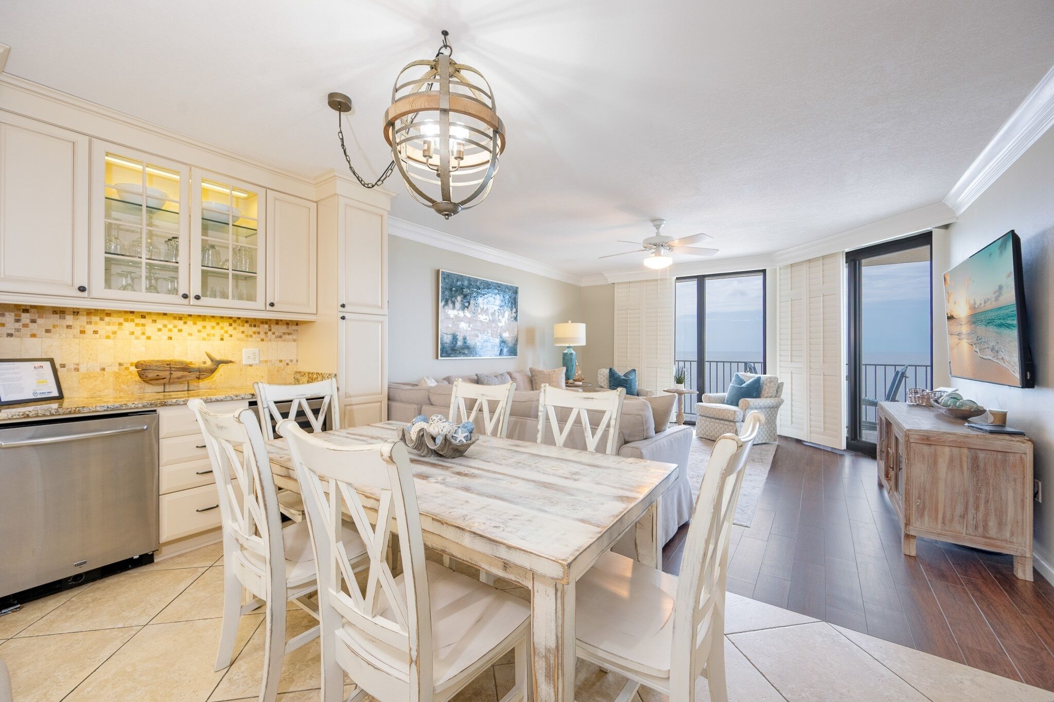 A spacious kitchen with white cabinetry and a dining area with a wooden table and white chairs.