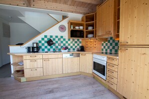 Eine Küche mit Holzausstattung, einer Mikrowelle, einer Kaffeemaschine und einer karierten Spritzschutzwand.