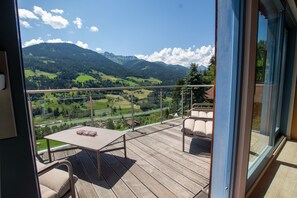 Ein Balkon mit Tisch und Stühlen, mit Blick auf eine gebirgige Landschaft.