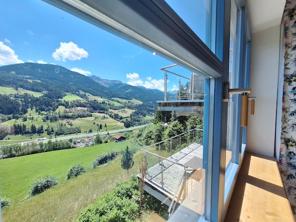 Ein Balkon mit Metallgeländer und Blick auf eine gebirgige Landschaft.