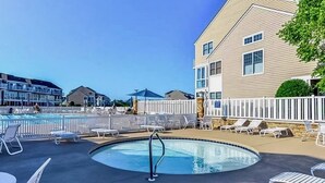 A swimming pool with lounge chairs and a white fence.