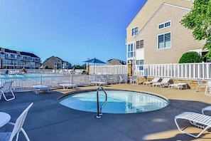 A swimming pool with lounge chairs and a white fence.