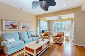 Ein Wohnzimmer mit Sofa, Sesseln, Couchtisch und Deckenventilatoren.
