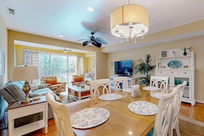 A living room with a dining table, chairs, a TV, and a ceiling fan.