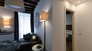 Et moderne hotelværelse med en sofa, et lille bord, en lampe og en seng i det tilstødende rum.