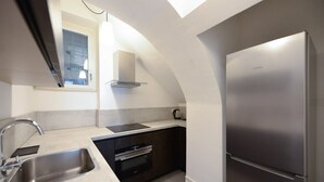 Et moderne køkken med et rustfrit stål køleskab, indbygget ovn og et vindue over vasken.