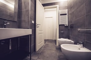 Ein modernes Badezimmer mit einem großen Waschbecken, einem Bidet und einer Toilette.