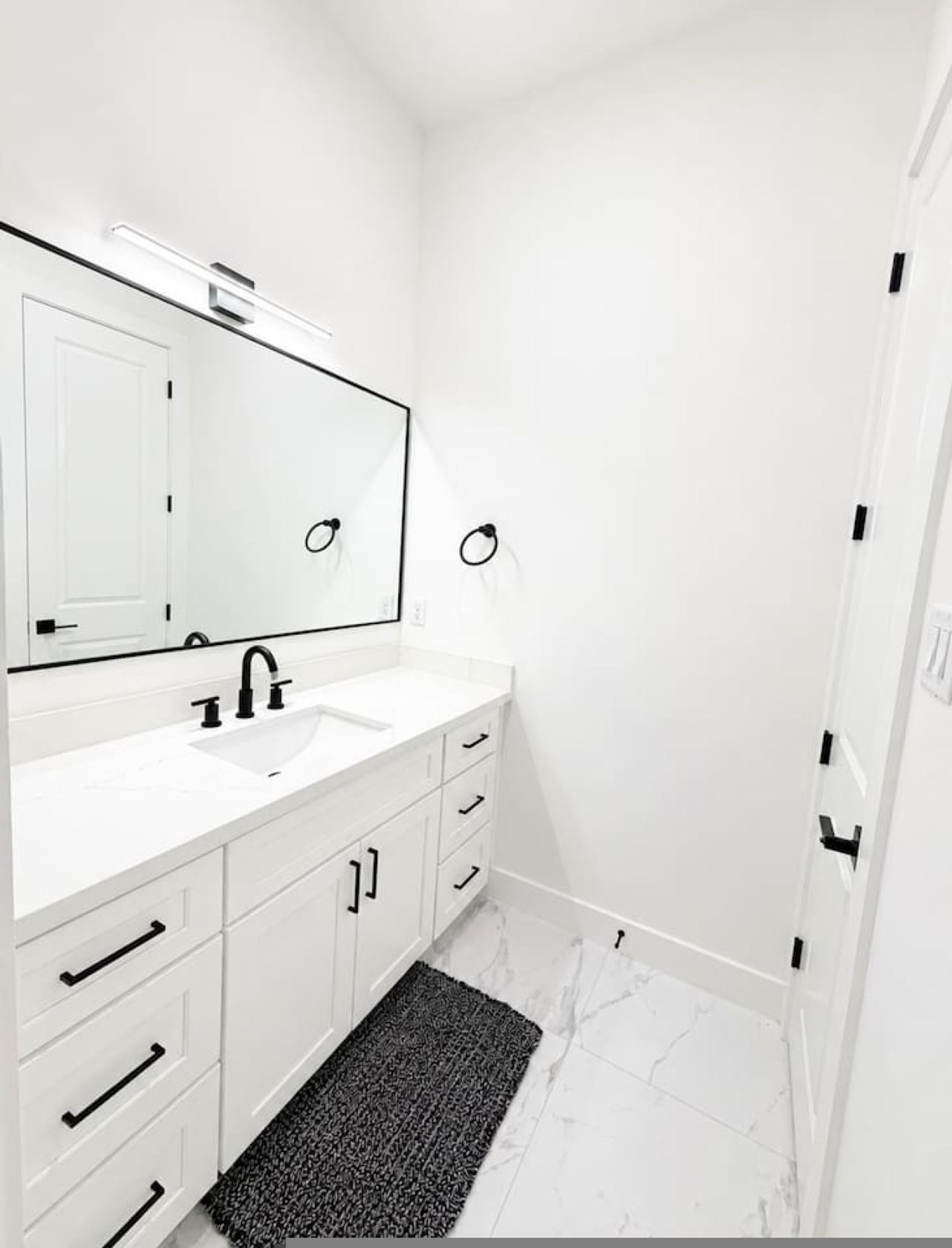 A modern bathroom with a white sink, mirror, and marble floor.