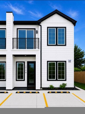 A two-story building with a white exterior, black-framed windows, and a black roof. - Modern 3BR Near UH Downtown Stadiums (Houston)