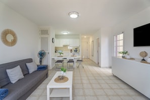 A modern living room with a sofa, a coffee table, and a dining area with chairs and a table. - Apartment Balcon del Atlantico, Costa Adeje (Playa de las Américas)
