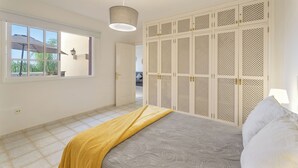 Un dormitorio con cama, ventana, armario y lámpara colgante.