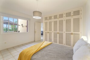 A bedroom with a bed, a window, a wardrobe, and a hanging light fixture. - Apartment Balcon del Atlantico, Costa Adeje (Playa de las Américas)