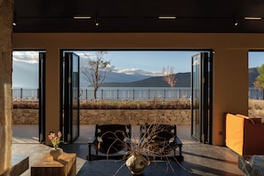 A room with a stone wall, two chairs, a table, and a vase with flowers.