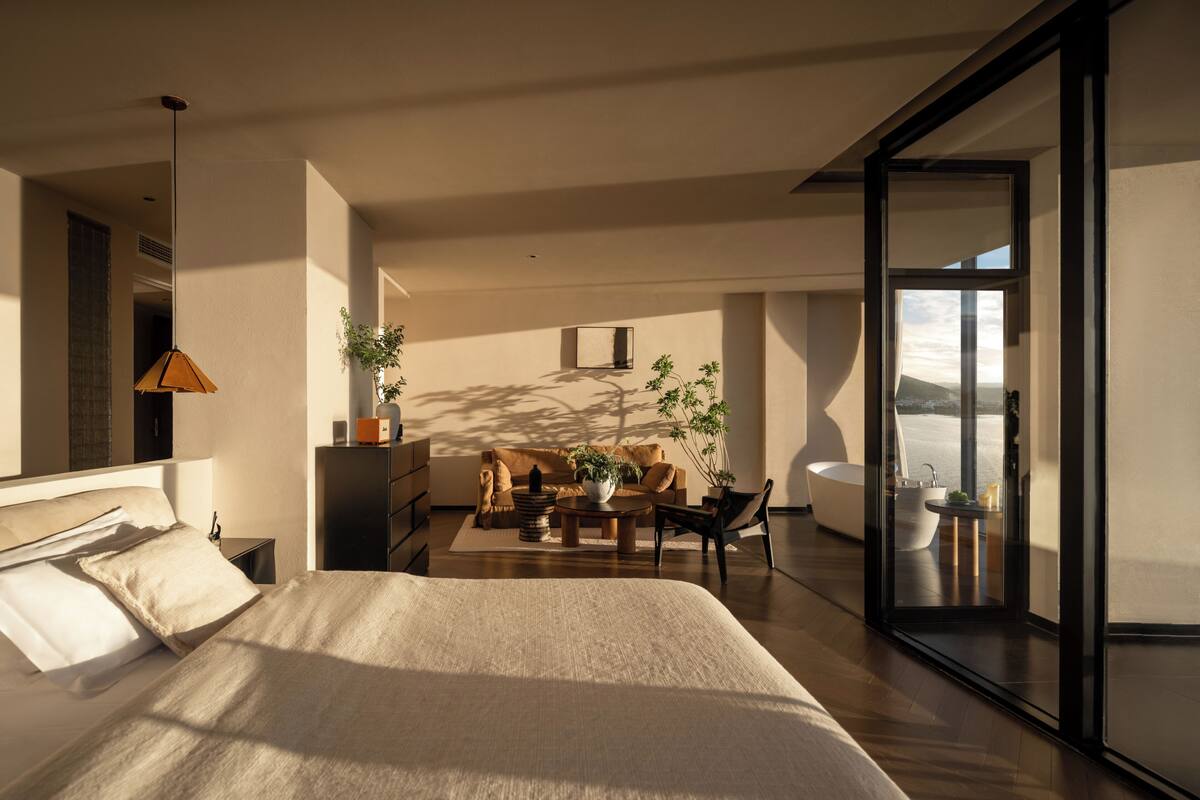 Un dormitorio moderno con una cama grande, un escritorio, un sofá y vistas al exterior.