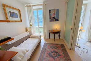 Ein Schlafzimmer mit Bett, Nachttisch, Lampe, Teppich und einem Fenster mit Blick.