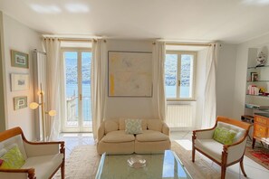 Ein Wohnzimmer mit einer Couch, zwei Sesseln, einem Couchtisch und einem Bücherregal.