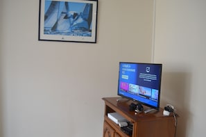 Un téléviseur posé sur un meuble en bois, avec un tableau encadré au-dessus.