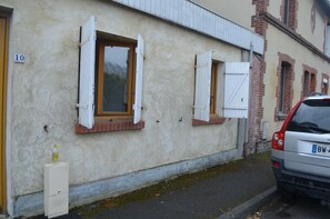 A building with two windows, a door, and a parked car.