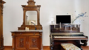 Un piano avec un banc, un miroir et un téléviseur posé sur un meuble.