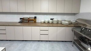 Una cocina moderna con armarios de colores claros, encimera de madera y una parrilla de acero inoxidable.