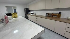 Eine moderne Küche mit Marmorarbeitsplatte, weißen Schränken und einem eingebauten Backofen.