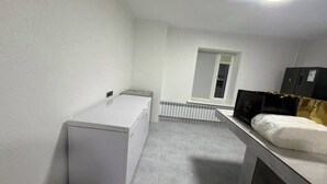Una habitación pequeña y moderna con una cama, un escritorio, un radiador y una ventana.