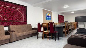 Un salón de conferencias con una larga mesa, varias sillas, un sofá y un muro decorativo.