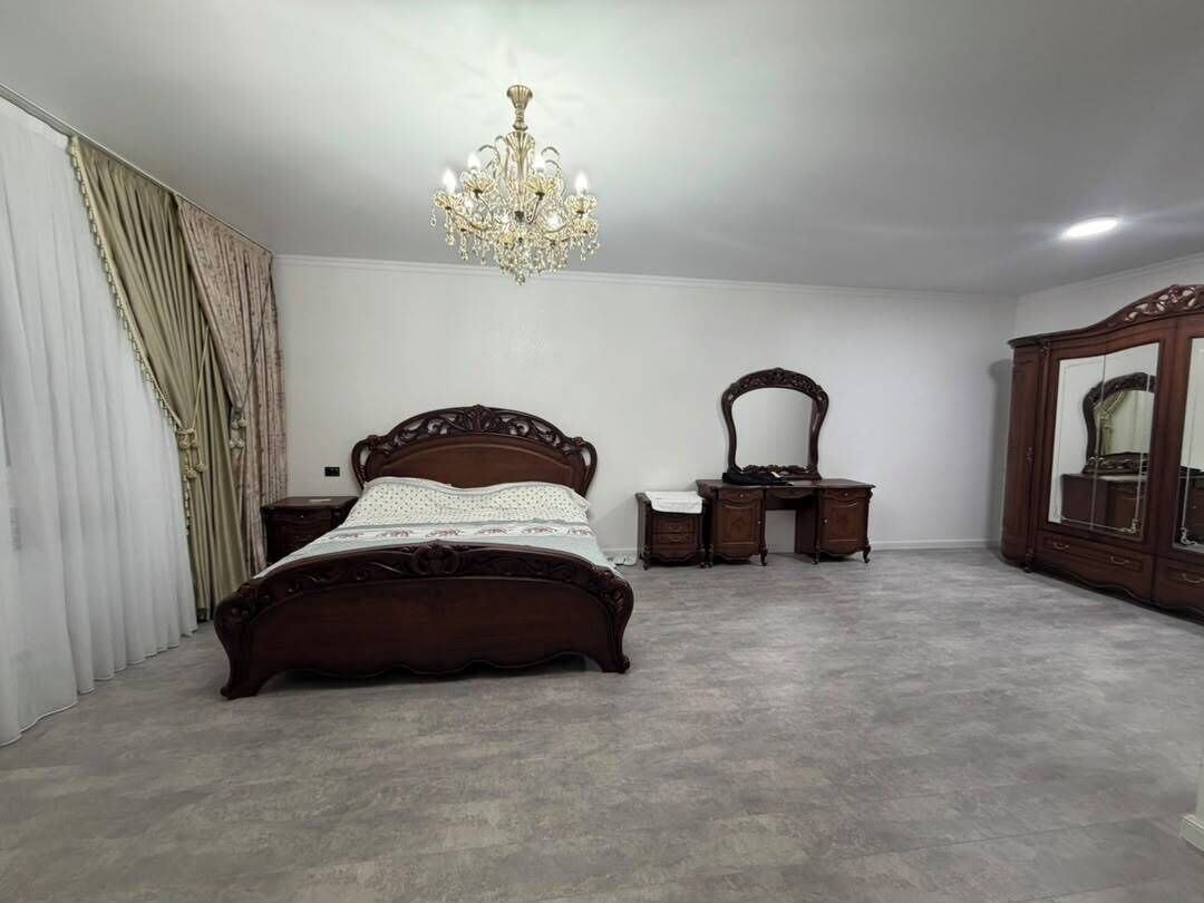 Quarto com uma cama grande, cômoda, espelho e lustre.