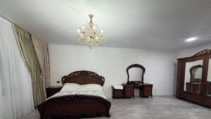 Ein Schlafzimmer mit einem großen Bett, einem Schminktisch, einem Spiegel und einer Kristallleuchter.