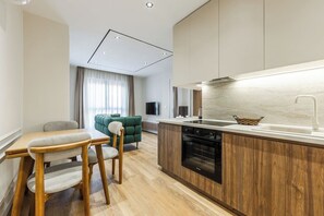 Eine kleine Küche mit Holzausbau, einem Einbauofen und einer Essecke mit Tisch und Stühlen.