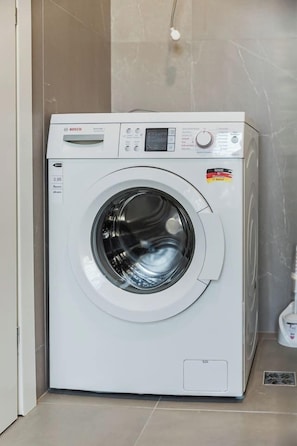 Eine Waschmaschine von Bosch in einem Badezimmer mit gefliesten Wänden und Boden.