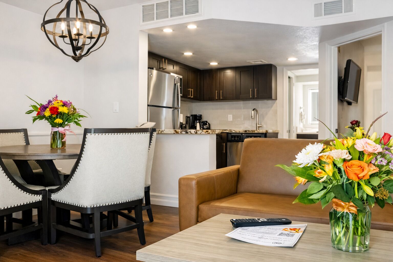 A modern living room with a dining area, a sofa, a coffee table, and a kitchen in the background.