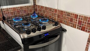 Une cuisine équipée d’une cuisinière à gaz, d’un four et d’un plan de travail recouvert de carreaux.