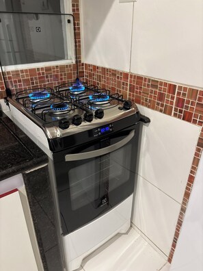 Eine Küche mit Gaskochfeld, Backofen und Fliesenrückwand.