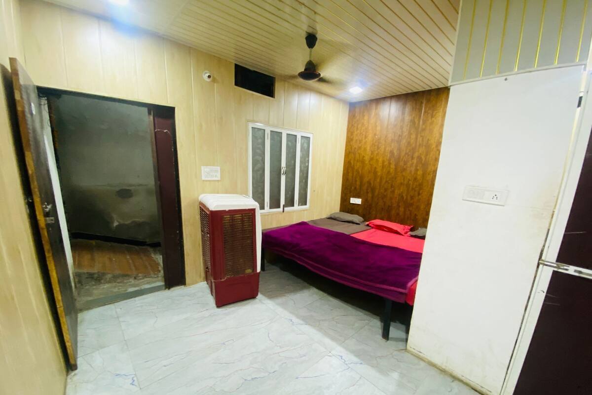 A bedroom with a bed, a heater, a wardrobe, and a window.