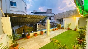 Un jardin sur le toit, agrémenté de plantes en pot, d’une petite pelouse et d’une structure métallique servant de toit.