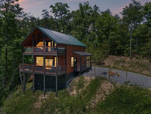 A two-story cabin with a balcony, surrounded by trees. - Exclusive Smoky Mountains Cabin w/ hot tub & views (Sevierville)