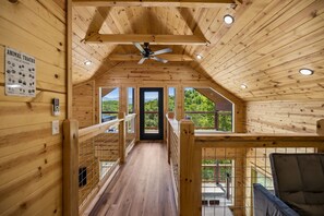 A wooden interior with a ceiling fan, a field guide sign, and a view through the door. - Exclusive Smoky Mountains Cabin w/ hot tub & views (Sevierville)