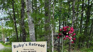 Señal de Ruby's Retreat con ilustración de una tienda de campaña, ubicada en 1 Beaver Lane, Franklin, ME 04634.