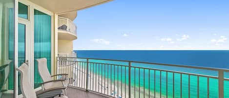 Een balkon met uitzicht op de oceaan, een stoel en een tafel.
