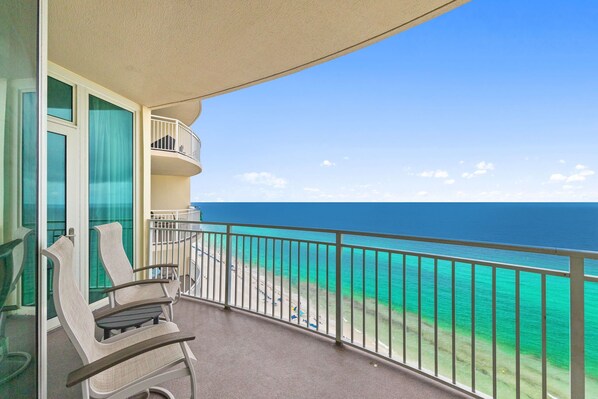 A balcony with a view of the ocean, a chair, and a table. - Aqua 2009 Oceanfront Primary King Bedroom/High Clean Standard/Wifi (Panama City Beach)