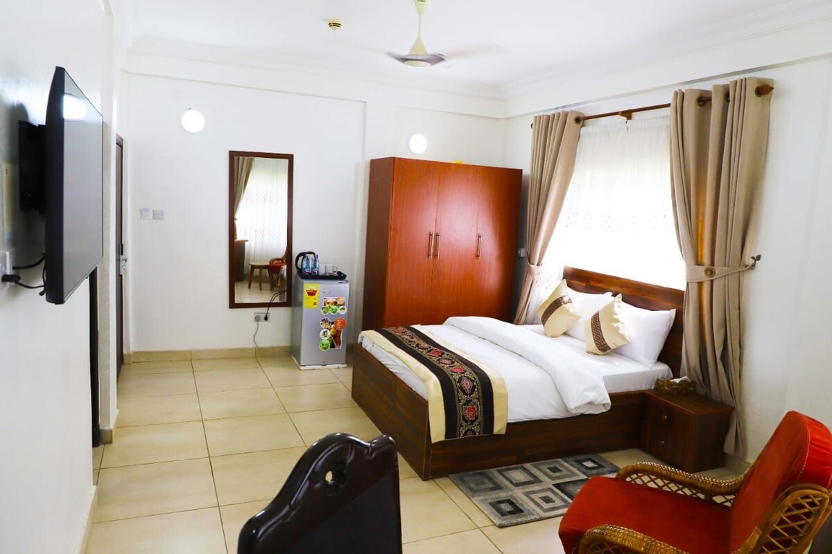 Una camera d'albergo con un letto, un armadio, una televisione e un piccolo tavolo.