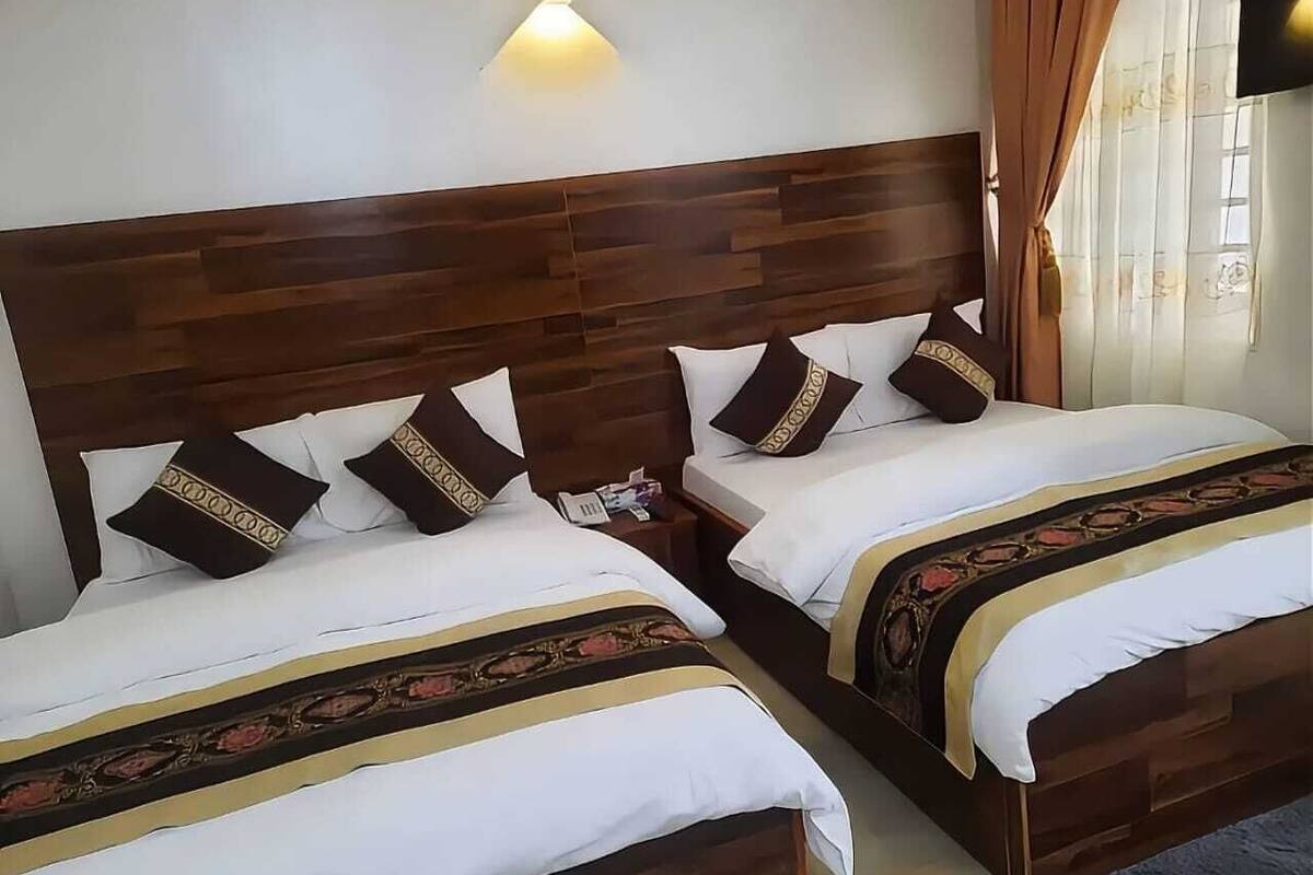 Un lit double avec une tête de lit en bois, une literie blanche et des coussins décoratifs.