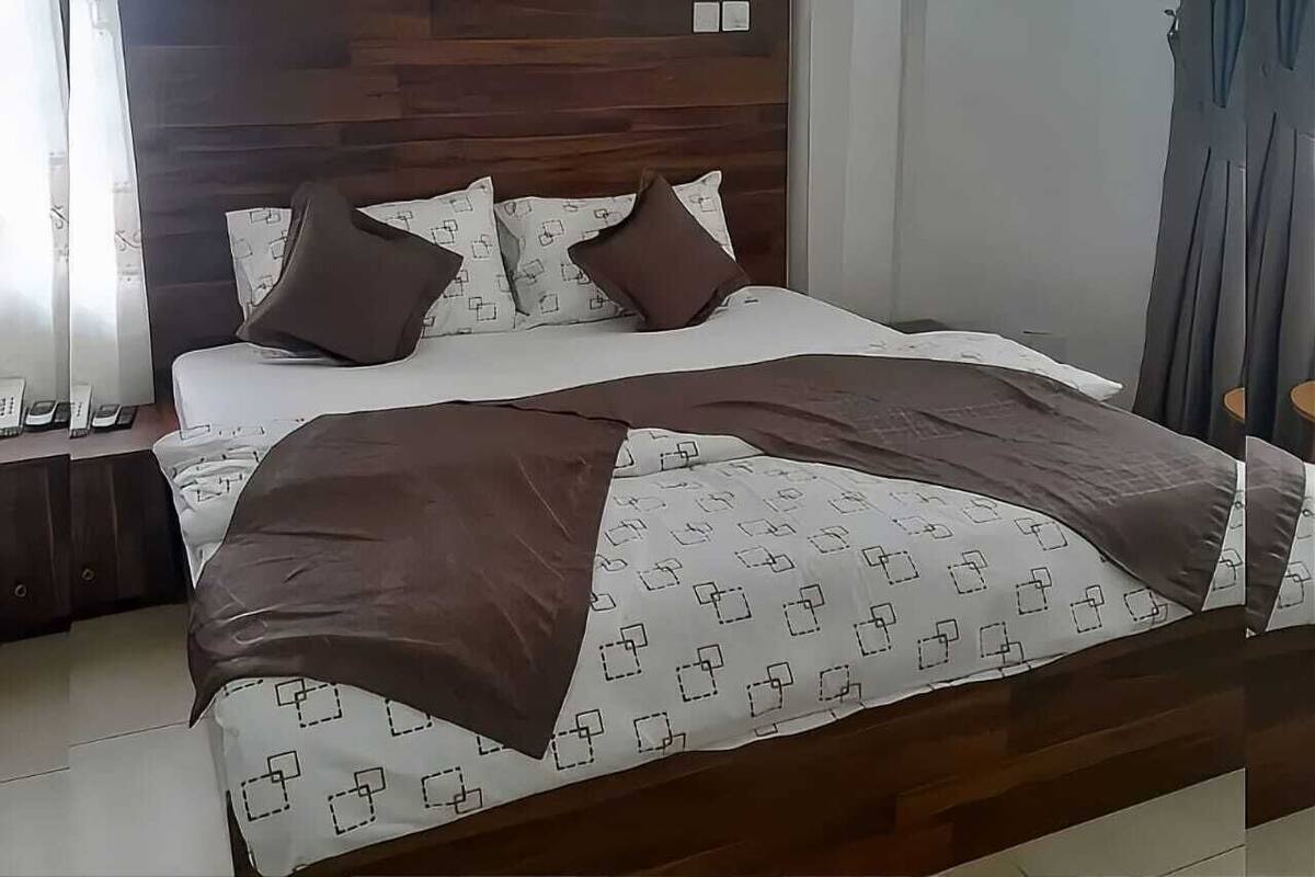 Un lit avec une couvre-lit à motifs, des oreillers et une couverture.